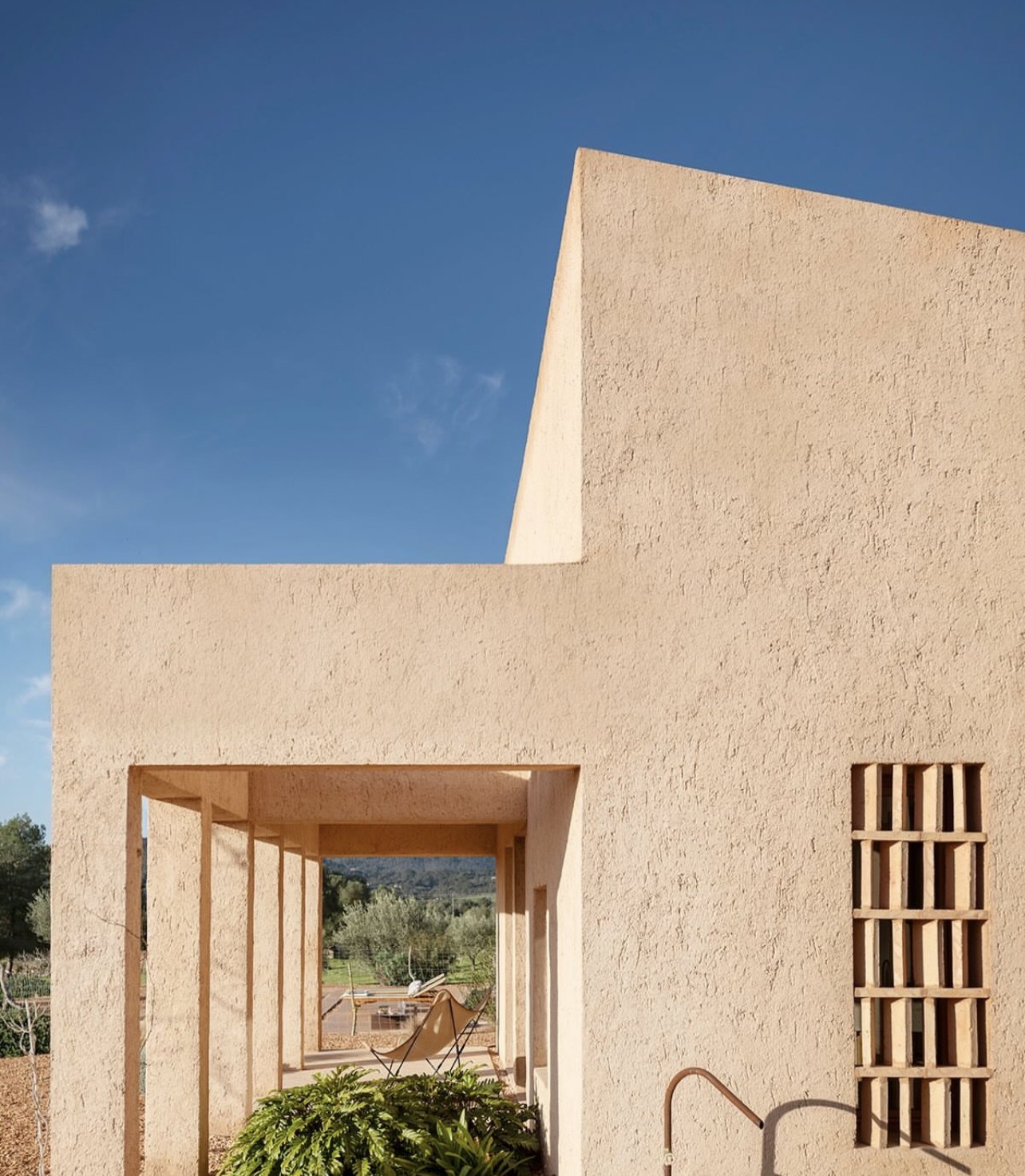 Reference image: an ochre plastered house with a deep portico and a timber lattice window.