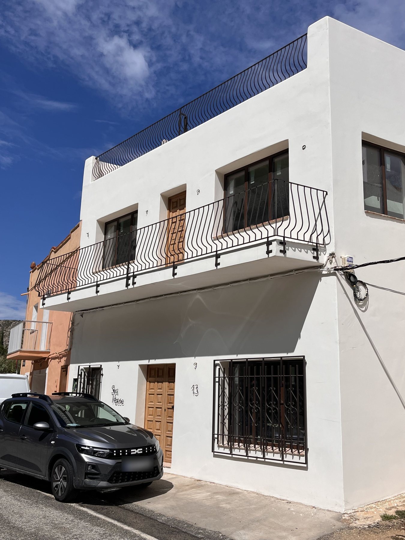 Sea House, Granadella: white façade with wrought-iron balcony, wooden doors and the house number 13.
