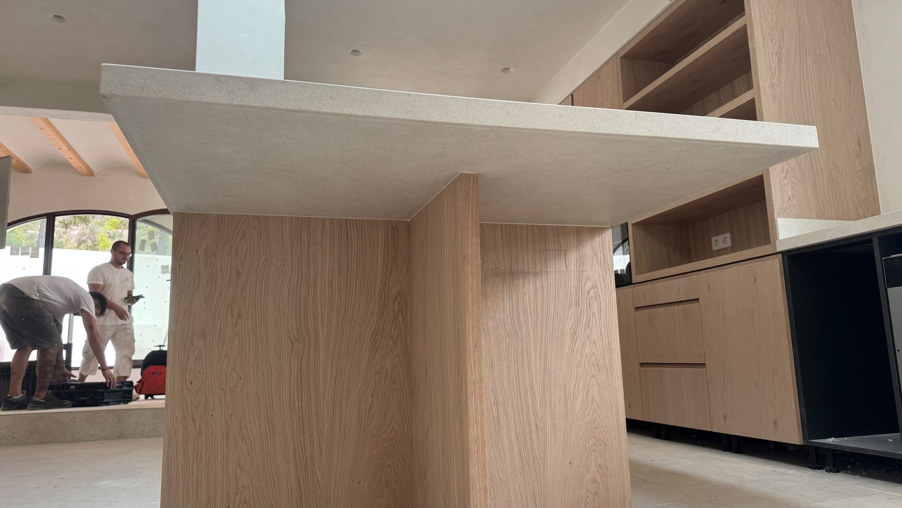Kitchen island seen from below: oak base and thick pale stone top.